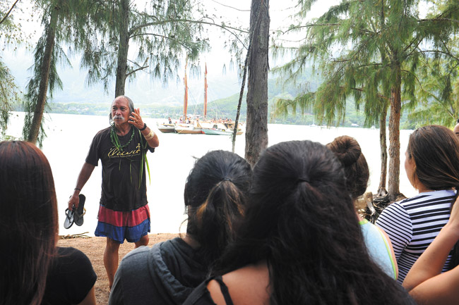 Longtime Hakipuu resident and teacher Calvin Hoe explains to Kamehameha Schools students how the Hokule'a (in background) is family. The beloved canoe and its crew visited the Hakipuu-Kualoa area in early October, along with similar celebrations all along the Windward side as part of the 'Malama Hawaii' leg of its upcoming world voyage next May. Photo by Lawrence Tabudlo, ltabudlo@midweek.com.
