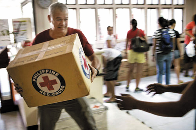Red Cross volunteers and staff work quickly handling food items at Philippine Red Cross headquarters in response to Typhoon Haiyan. The Hawaii Red Cross, meanwhile, has set up a hotline here for tracing family members affected by the deadly storm that slammed into the central Philippines on Nov. 8. Photo from the Finnish Red Cross.