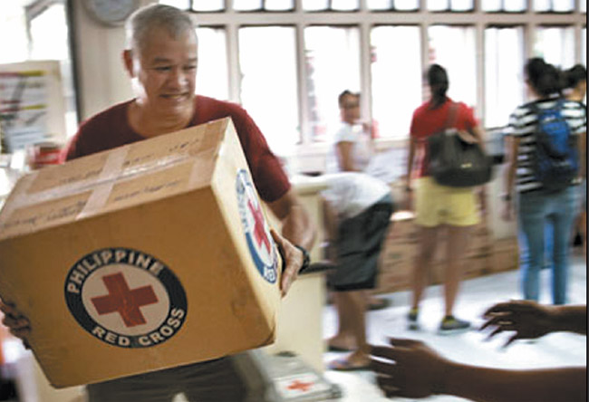 Red Cross volunteers and staff work quickly handling food items at Philippine Red Cross headquarters in response to Typhoon Haiyan. The Hawaii Red Cross, meanwhile, has set up a hotline here for tracing family members affected by the deadly storm that slammed into the central Philippines on Nov. 8. Photo from the Finnish Red Cross.