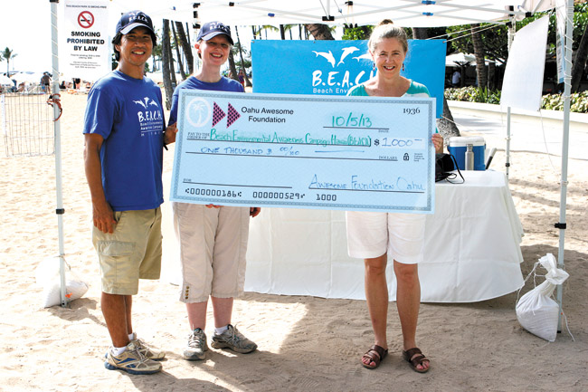 Dean Otsuki and Suzanne Frazer, co-founders of Beach Environmental Awareness Campaign Hawaii, accept a $1,000 grant from Awesome Foundation of Oahu representative Donna Ambrose (right). Photo courtesy of B.E.A.C.H. 