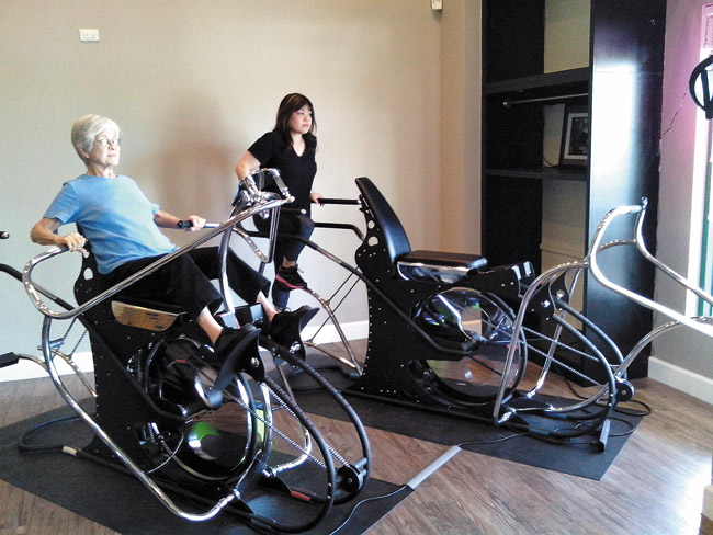 Jeanne Oshiro (left) and Celeste Oshiro Wong work out on the ROM machines at RomGym Waipio. Celeste Oshiro Wong and her husband opened RomGym Waipio in January. Photo courtesy of RomGym Waipio.