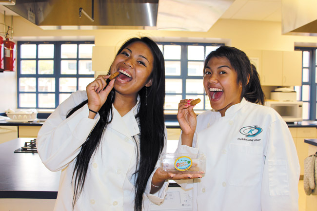 Kapolei High School graduates Jalen Payongayong (left) and Kelsey Cruz take a bite out of their very own award-winning power cookies, Aina Bites, developed in the school's culinary lab and headed for a national competition. Photo by Christina O'Connor.