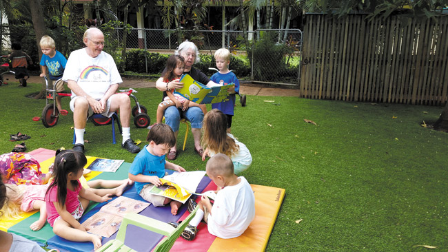 Rev. Samuel Cox and Carolyn Anderson, residents of Pohai Nani Retirement Community and newly minted 'foster grandparents,' share a somewhat intense story hour with eager little readers at Seagull School in Kailua. Photo from Seagull Schools.