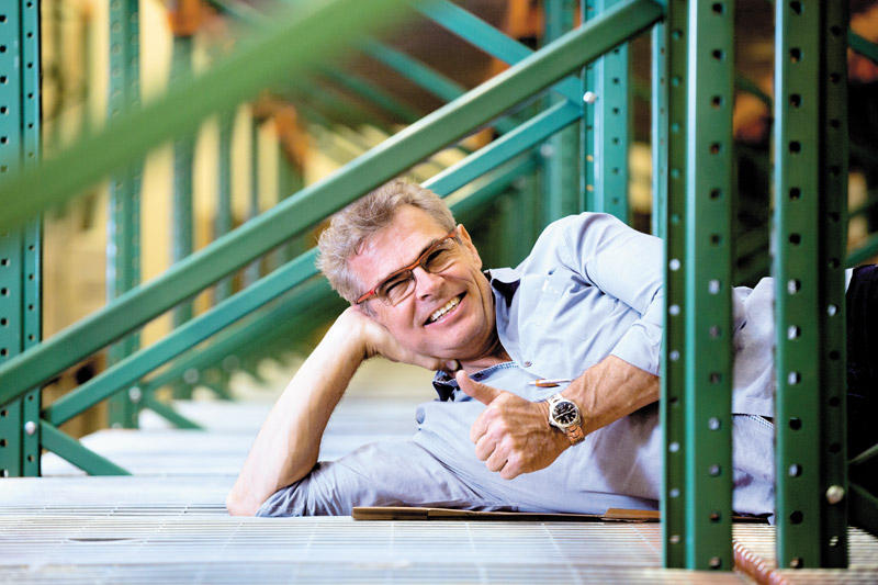 Owner Thomas Sorensen reclines on one of the empty shelving units in the new warehouse